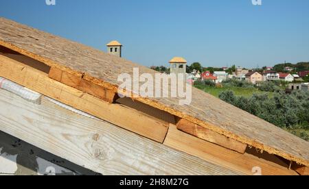 Construction de toitures.Un gros plan d'un toit en construction à l'étape de la couverture de toit, a installé le tablier de toit en panneaux OSB sur des planches de bois et le brac de bois Banque D'Images