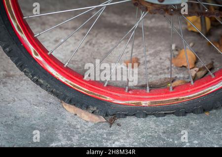 Gros plan d'un pneu de vélo plat vieux et rouille sur fond de ciment Banque D'Images