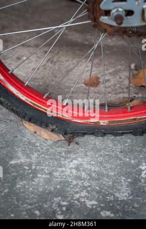 Gros plan d'un pneu de vélo plat vieux et rouille sur fond de ciment Banque D'Images