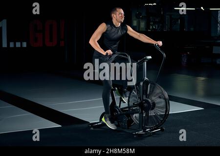 Un homme de fitness utilise un vélo d'air pour faire de l'exercice cardio à la salle d'entraînement fonctionnelle. Banque D'Images