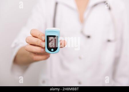 Oxymètre de pouls avec main du médecin isolé sur blanc.Mesure de la saturation en oxygène, de la fréquence de pouls et des niveaux d'oxygène.Le concept du numérique portable Banque D'Images