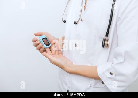 Oxymètre de pouls avec main du médecin isolé sur blanc.Mesure de la saturation en oxygène, de la fréquence de pouls et des niveaux d'oxygène.Le concept du numérique portable Banque D'Images
