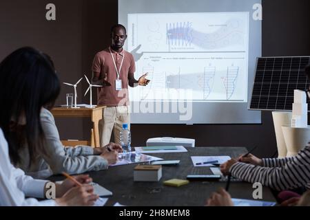 Jeune orateur africain debout près du grand moniteur et parlant à la conférence pour les gens d'affaires Banque D'Images