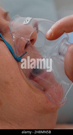 Gros plan du médecin appliquant un masque à oxygène sur un patient malade souffrant de problèmes respiratoires.Femme à la retraite avec la maladie recevant l'assistance médicale et l'aide avec l'équipement de medic pour les soins de santé Banque D'Images