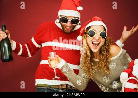 Un couple fou qui fête le temps de Noël en buvant du champagne - Focus sur les lunettes de soleil pour femme Banque D'Images