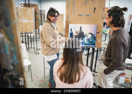 Professeur mature travaillant avec des étudiants en art pendant la classe de peinture à l'école - Focus sur le visage de femme Banque D'Images