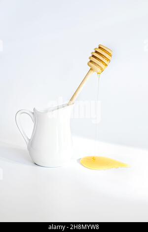 Le miel coule du bâton de miel en dinde. Les miels font sur fond blanc. Carafe à crème pour le petit déjeuner Banque D'Images