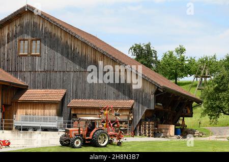 Tracteur Fiat avec faneuse de rond-point devant un bâtiment stable Banque D'Images