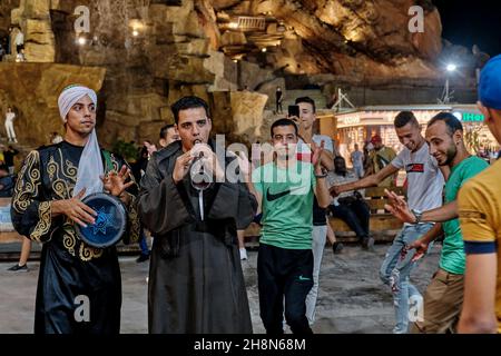 Deux jeunes égyptiens jouant des instruments folkloriques sur la place de la ville le soir.certaines personnes dansant joyeusement Banque D'Images