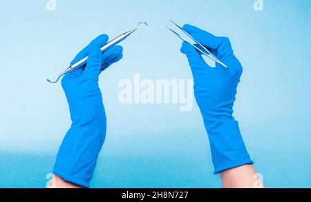 Mains dans des gants bleus tenant des outils dentaires Banque D'Images
