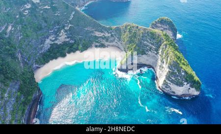 Un drone survole le point de vue de Kelingking Beach jusqu'à la pointe, puis s'incline sur un chemin sur la crête Banque D'Images