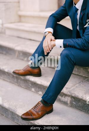 Homme dans un costume bleu assis sur les marches de pierre.Gros plan Banque D'Images