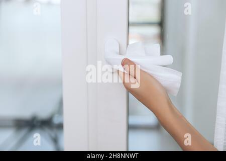 Nettoyage des poignées de porte à l'aide d'une lingette humide antiseptique et de gants.Femme main utilisant une serviette pour nettoyer la liaison de la porte de la chambre à la maison.Désinfectez la prévention des surfaces dans Banque D'Images