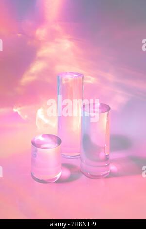 trois podiums en verre transparent sur fond rose pastel Banque D'Images