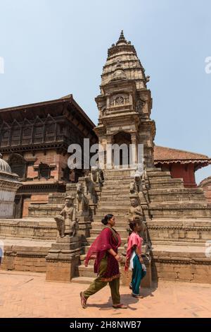 Deux femmes marchent près du temple hindou Siddhi Laxmi sur la place Durbar.Cité médiévale de Near, Bhaktapur, Népal.Les femmes portent les alpc traditionnels Banque D'Images