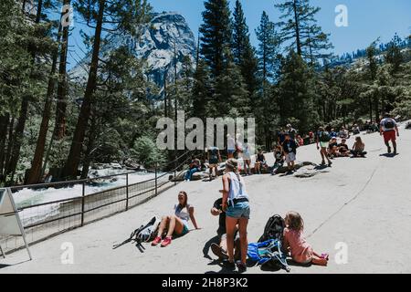 Les touristes affluent vers les chutes de Lower Yosemite dans le parc national de Yosemite lors d'un après-midi de printemps. Banque D'Images