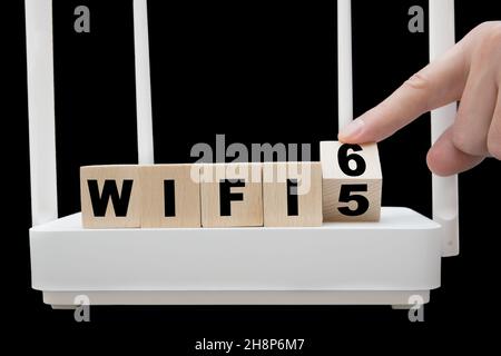 Doigt tournant un cube en bois illustrant la transition du WiFi 5 au WiFi 6.Changer l'infrastructure pour prendre en charge la toute dernière norme de mise en réseau sans fil Banque D'Images