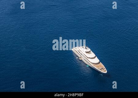 Drone aérienne photo de haut en bas de yacht exotique de luxe avec pont en bois ancré dans l'île de la mer Égée avec la mer bleu profond, Grèce. Banque D'Images