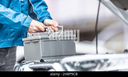 Le mécanicien remplace la batterie de la voiture dans l'atelier de garage. Banque D'Images