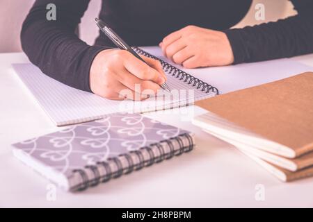 Détail des mains écrivant avec les fournitures scolaires Banque D'Images