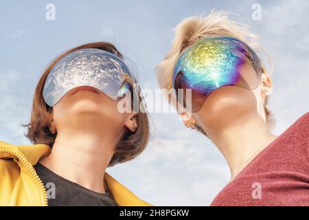 deux jeunes femmes dans des masques miroirs qui couvrent complètement leur visage regardant vers l'avant.Vue à angle bas Banque D'Images