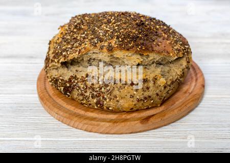 Pain naturel de pain de levain sans levure avec graines de sésame, lin, chia, graines de tournesol, sur une planche de bois sur la table, gros plan. Banque D'Images