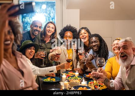 des amis qui toastent et font du selfie au dîner, un grand groupe de personnes qui s'amusent et se célèbrent, le rassemblement social et l'amitié conce Banque D'Images