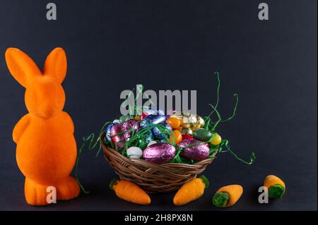 Lapin orange avec carottes et panier de Pâques rempli avec œufs doux Banque D'Images