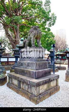 Une statue en pierre d'un lion parmi de nombreuses lanternes de bronze au sanctuaire Ueno Toshogu dans le parc Ueno, Tokyo. Banque D'Images