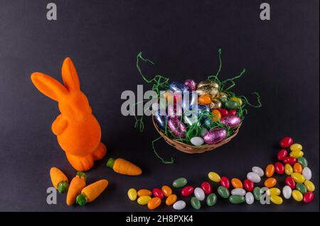 Lapin orange avec carottes et panier de Pâques rempli avec œufs doux Banque D'Images