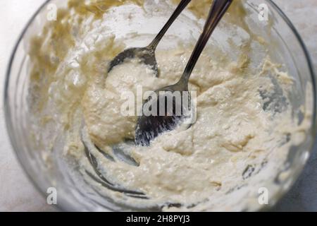 Grand bol en verre avec restes de pâte et deux cuillères à soupe, vue rapprochée d'en haut. Banque D'Images