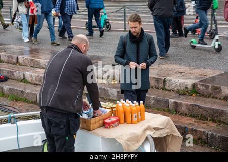 Homme vendant du jus d'argousier et de la confiture en bateau amarré sur la place du marché à Helsinki, en Finlande Banque D'Images