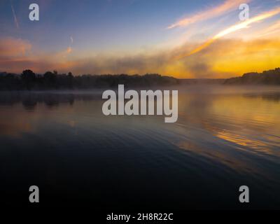 Ambiance positive spectaculaire au lever du soleil, le moment de la naissance du brouillard.Le brouillard glisse au-dessus de la rivière sur le fond du soleil levant.Brumisateur sur le g Banque D'Images