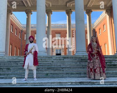 Parc Osterley Richmond. Mari et femme ayant des photos pour un mariage sikh en Angleterre debout des marches et des piliers de poser des piliers mariés Banque D'Images