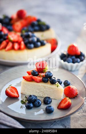 Cheesecake New-yorkais à la vanille décoré de myrtilles fraîches et de fraises Banque D'Images