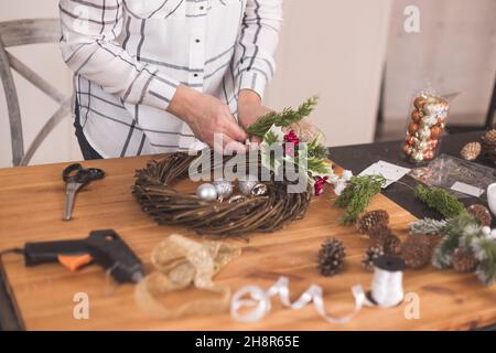 Femme artisanale faisant couronne de Noël sur une table parmi par le décor du nouvel an.Passe-temps pour femmes.Préparation du concept de vacances.Noël par semaine Banque D'Images