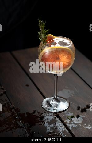 Bebida alcohólica (trago de gin et tonique) con rodaja de pomelo y hielo en rústica mesa de madera mojada. Banque D'Images