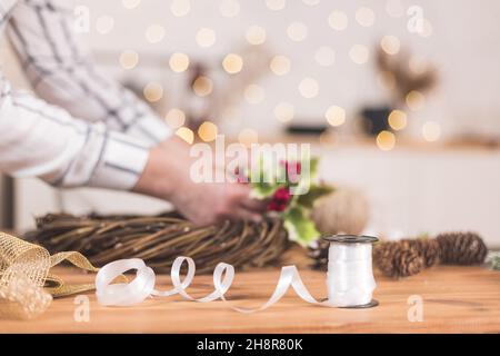 Femme artisanale faisant couronne de Noël sur une table parmi par le décor du nouvel an.Passe-temps pour femmes.Préparation du concept de vacances.Noël par semaine Banque D'Images