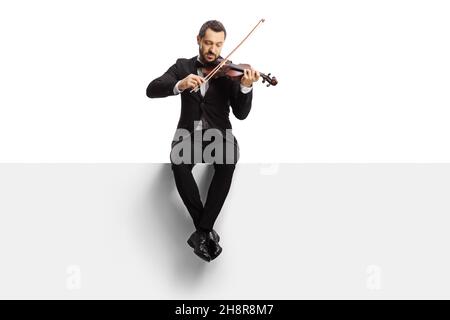 Prise de vue en longueur d'un violoniste assis sur un panneau vierge et jouant un violon isolé sur fond blanc Banque D'Images