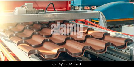 Tuiles de toit en acier dans machine de formage de tôles en usine de travail des métaux. Banque D'Images