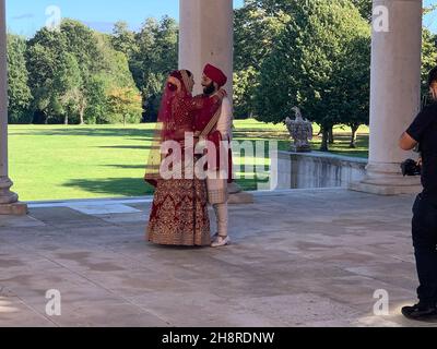 Parc Osterley Richmond. Mariée et marié ayant des photos pour un mariage indien Sikh en Angleterre avec mari sous piliers avec couple de turban marié tenir Banque D'Images