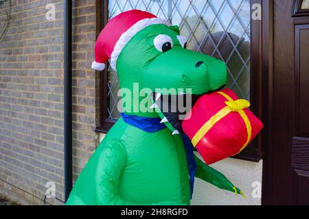 Grand dinosaure de fête en plastique de fantaisie vert à l'extérieur d'une maison à Surrey en décembre Banque D'Images