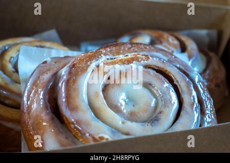 Vue inclinée d'une boîte de pâtisseries ouverte remplie de grands petits pains à la cannelle faits maison Banque D'Images