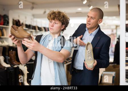 Homme et adolescent qui choisissent des chaussures dans la boutique de chaussures Banque D'Images