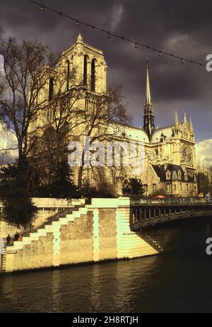 AVR 1984: Cathédrale notre Dame d'or et pont au Double pont sur la Seine avec nuage foncé peu avant le coucher du soleil à Paris, France Banque D'Images