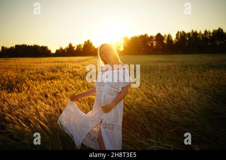 grossesse, personnes, repos, concept d'attente, femme enceinte heureuse se tient dans le champ et touche la nature du ventre Banque D'Images