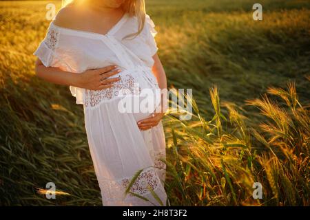 grossesse, personnes, repos, concept d'attente, femme enceinte heureuse se tient dans le champ et touche la nature du ventre Banque D'Images