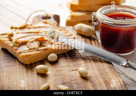 Vue à angle bas du sandwich au beurre d'arachide sur la planche à découper avec toasts et confiture de côté.Concept de saine alimentation Banque D'Images