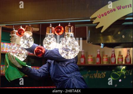 Cologne, Allemagne.02e décembre 2021.Une femme nettoie les lampes dans une cabine au marché de Noël en face de la cathédrale.Credit: Henning Kaiser/dpa/Alay Live News Banque D'Images