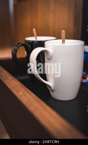 Mise au point sélective d'une tasse à café blanche et noire avec un agitateur en bois Banque D'Images